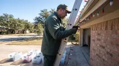Installer taking down Christmas lights from a home in Austin, Texas for labeled storage