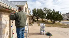 Installer taking down Christmas lights from a limestone Hill Country home in Cedar Park, TX for labeled storage