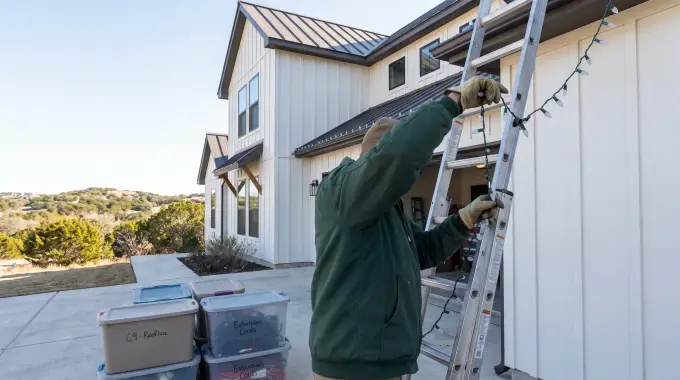 Installer taking down Christmas lights from a modern farmhouse home in Leander, TX for labeled storage