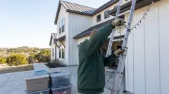 Installer taking down Christmas lights from a modern farmhouse home in Leander, TX for labeled storage