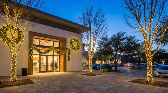 Commercial holiday lighting with wrapped trees and lit wreaths at a business in Cedar Park, TX