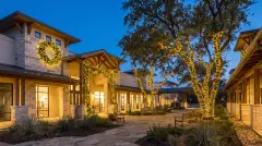 Commercial holiday lighting with wrapped trees and lit wreaths at a business in Lakeway, TX