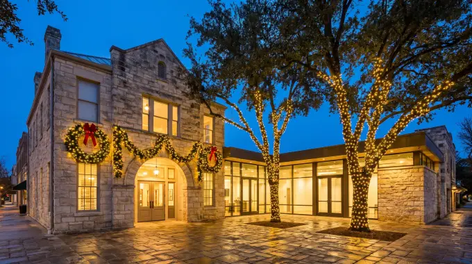 Commercial holiday lighting with wrapped trees and lit wreaths at a business in Round Rock, TX