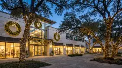 Commercial holiday lighting with wrapped trees and lit wreaths at a business in West Lake Hills, TX