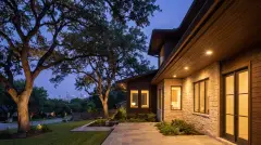 Permanent LED Christmas lights hidden under the eaves of a craftsman home under live oaks in Austin, TX