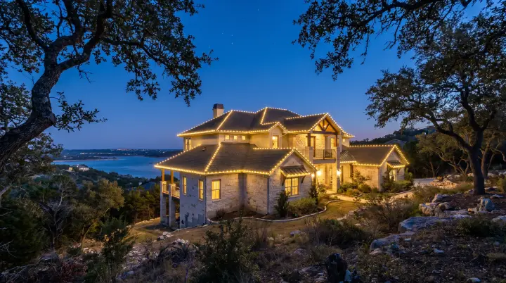 Custom-fit warm-white C9 Christmas lights outlining the roofline of a Lake Travis hillside estate in Lakeway, TX