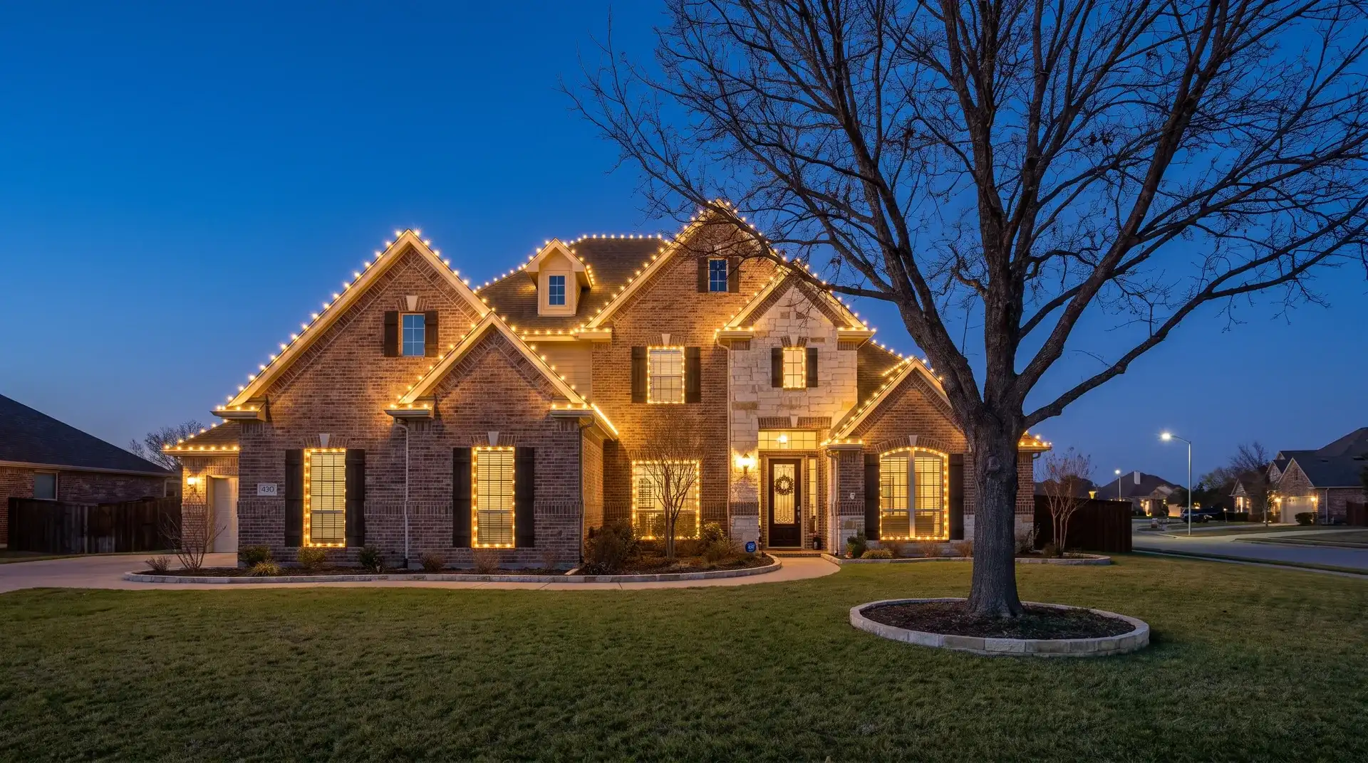 Custom-fit warm-white C9 Christmas lights outlining the roofline of a two-story suburban home in Pflugerville, TX