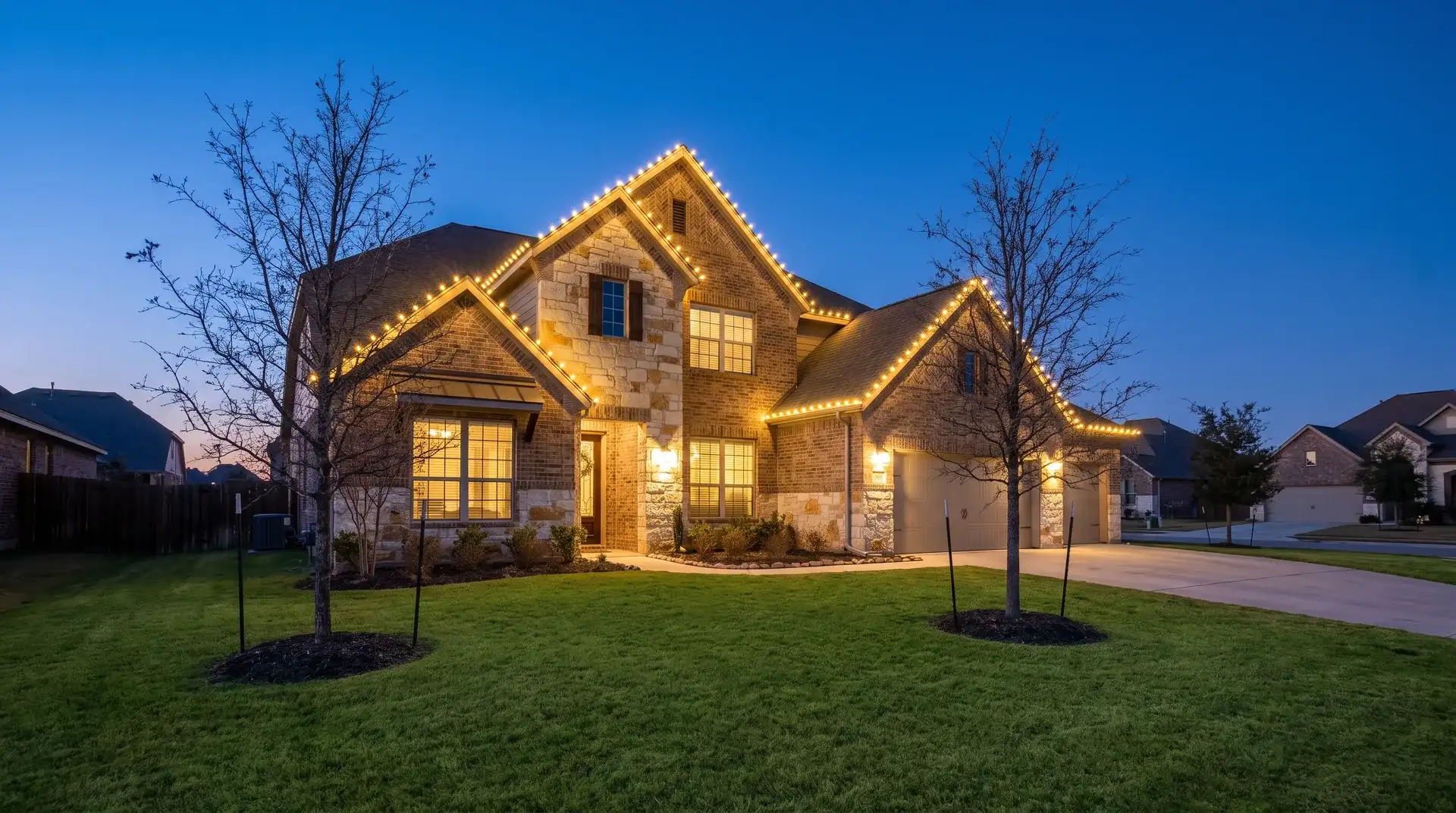 Custom-fit warm-white C9 Christmas lights outlining the roofline of a two-story brick home in Round Rock, TX