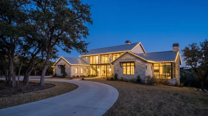 Custom-fit warm-white C9 Christmas lights outlining the roofline of a wooded hillside home in West Lake Hills, TX