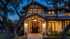 Pre-lit wreath and garland installed on the front entry of a craftsman home under live oaks in Austin, TX