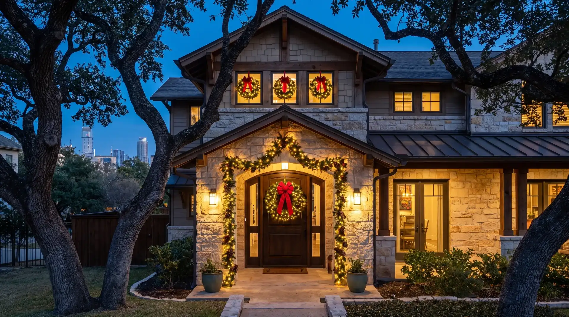 Pre-lit wreath and garland installed on the front entry of a craftsman home under live oaks in Austin, TX