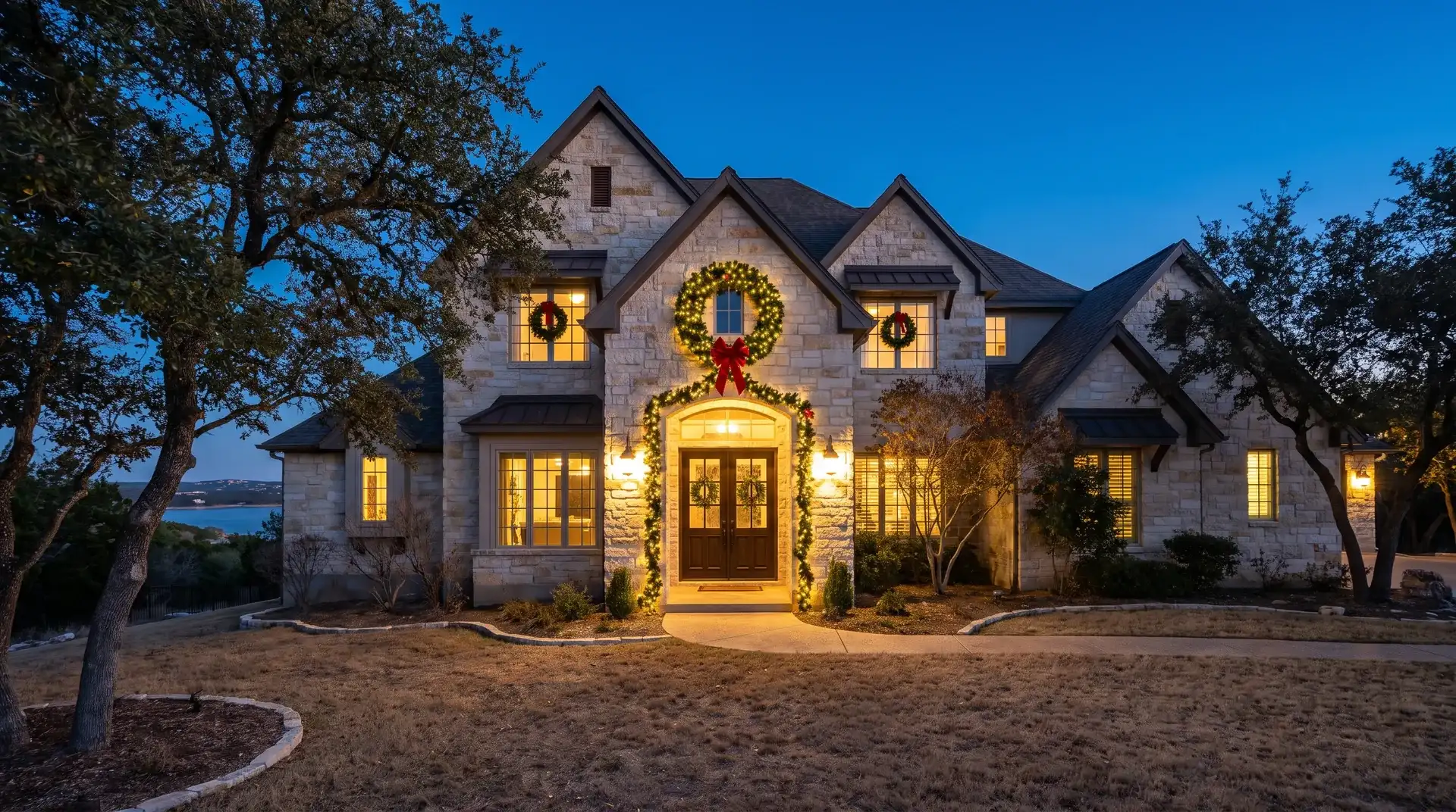 Pre-lit wreath and garland installed on the front entry of a Lake Travis hillside estate in Lakeway, TX