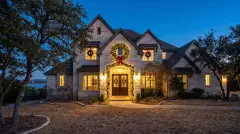 Pre-lit wreath and garland installed on the front entry of a Lake Travis hillside estate in Lakeway, TX