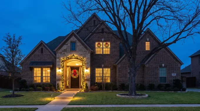 Pre-lit wreath and garland installed on the front entry of a two-story suburban home in Pflugerville, TX