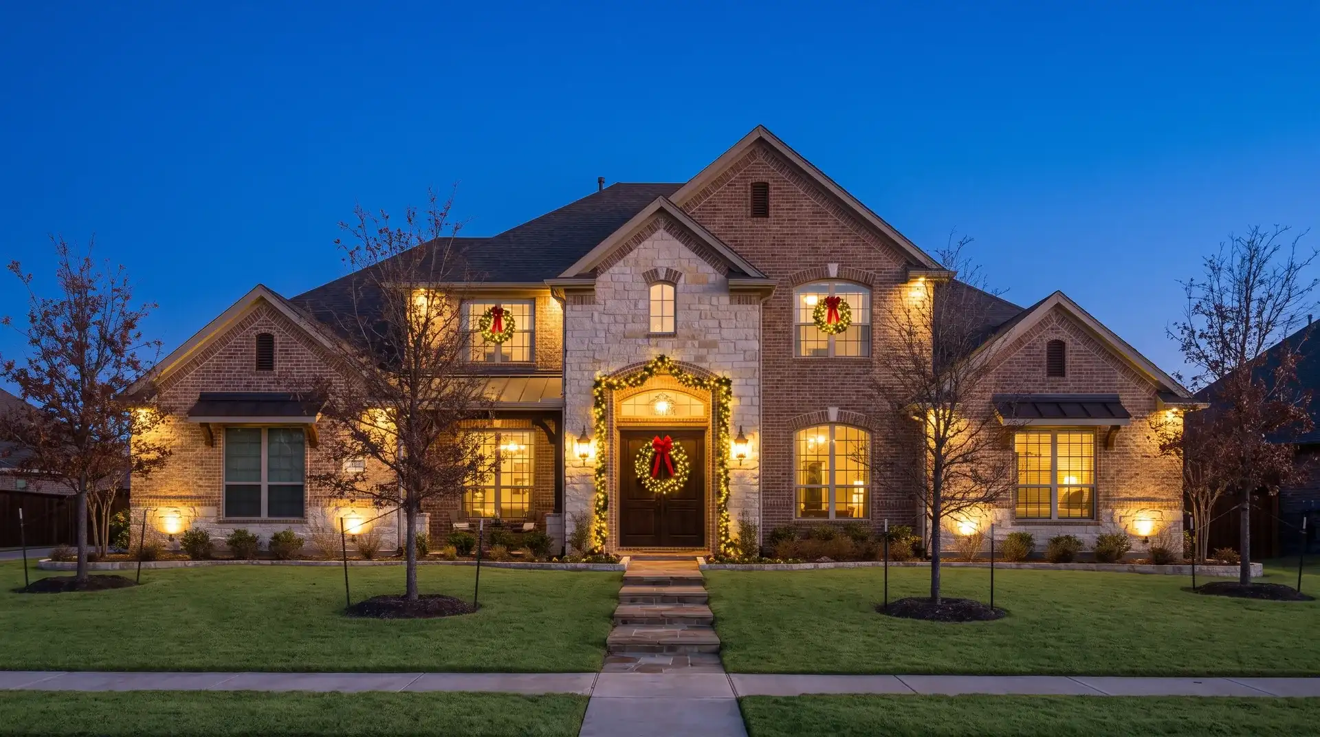 Pre-lit wreath and garland installed on the front entry of a two-story brick home in Round Rock, TX